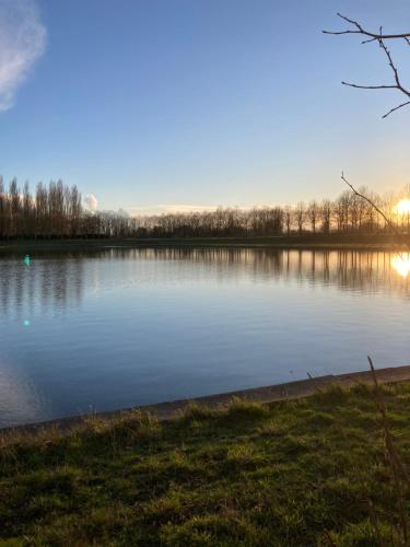 a view of a large lake at sunset at Château de la Thibaudière - Studio de Madame de Savary in Allonnes