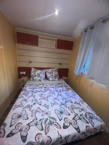 - une petite chambre dotée d'un lit avec un couvre-lit floral dans l'établissement Mobil home, à Saint-Chéron