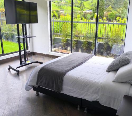 a bedroom with a bed and a flat screen tv at Comfort Campestre in Tabio