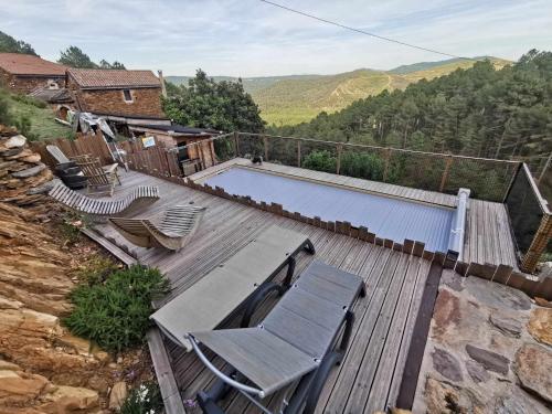 une terrasse en bois avec des chaises et une piscine dans l'établissement Les Combres, gîte nature avec piscine chauffée, à Malbosc