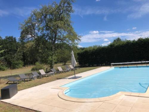 une grande piscine avec des chaises et un parasol dans l'établissement Charmant Domaine Solognot piscine, à Lassay-sur-Croisne