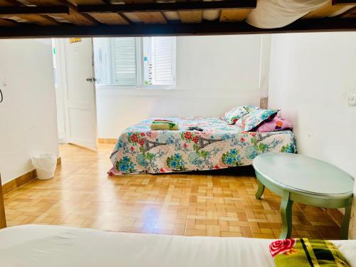 a bedroom with two beds and a table at Hostal Badillo SV in Cartagena de Indias