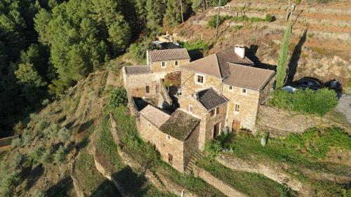 une vieille maison sur le flanc d'une colline dans l'établissement Les Combres, gîte nature avec piscine chauffée, à Malbosc