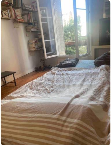 un grand lit dans une chambre avec une fenêtre dans l'établissement Chambre calme et lumineuse, à Paris