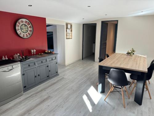 une cuisine avec une table en bois et un mur rouge dans l'établissement Appartement cosy proximité barrage Lavalette et Yssingeaux, à Saint-Jeures
