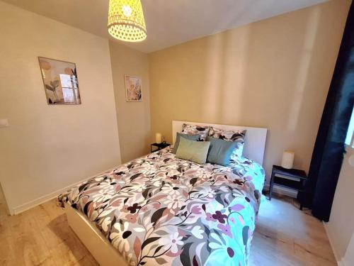 une chambre avec un lit avec une couette fleurie dans l'établissement T2 cosy 35 m2- centre historique Besançon, à Besançon