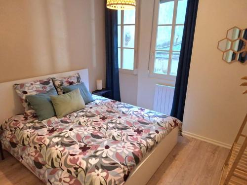 une chambre avec un lit avec un couvre-lit fleuri dans l'établissement T2 cosy 35 m2- centre historique Besançon, à Besançon