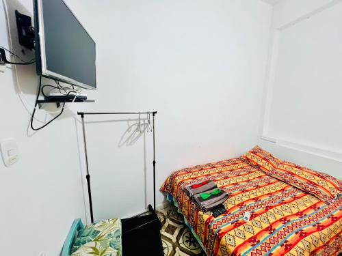 a room with a bed with a tv on a stand at Hostal Badillo SV in Cartagena de Indias
