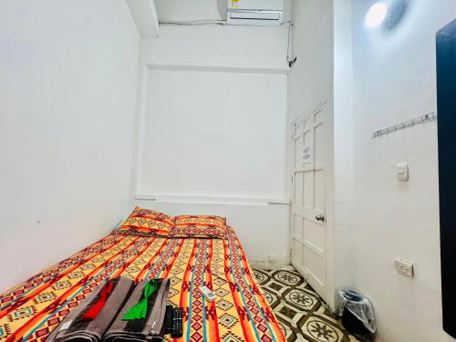 a small bedroom with a bed with a colorful blanket at Hostal Badillo SV in Cartagena de Indias