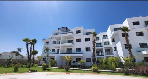 a white building with palm trees in front of it at Casas del mar cabo in Cabo Negro