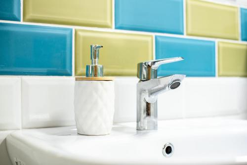 a bathroom sink with two faucets and a roll of toilet paper at Colours Plus in Sarajevo