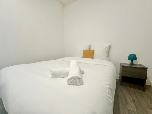 une chambre avec un lit blanc avec des serviettes dessus dans l'établissement Le Puits de Lumière, spacieux et atypique, à Limoges