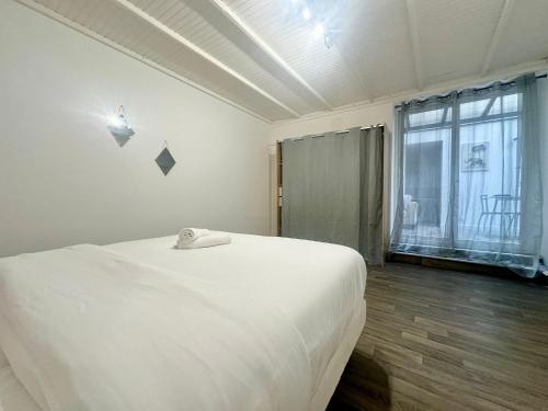 une chambre avec un lit blanc et une grande fenêtre dans l'établissement Le Puits de Lumière, spacieux et atypique, à Limoges