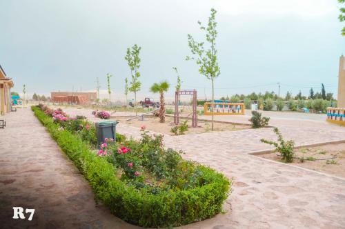 a park with flowers and a playground in the background at Chalets ITO Atlas Timnay in Midelt