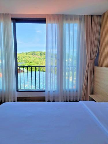 a bedroom with a bed and a large window at Rosetta Hotel Phu Quoc in Phu Quoc