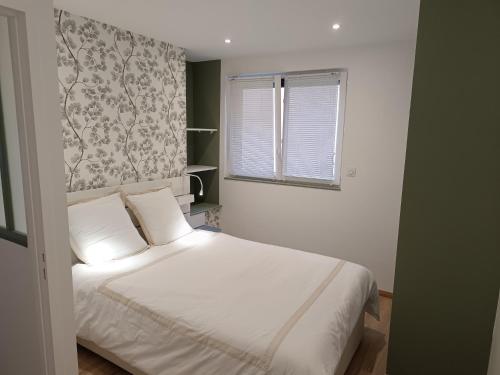 ein Schlafzimmer mit einem weißen Bett und einem Fenster in der Unterkunft aux nids douillets mayetois "les tourtereaux" in Mayet-de-Montagne