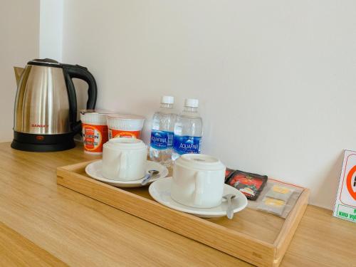 a wooden shelf with two cups and bottles of water at Rosetta Hotel Phu Quoc in Phu Quoc