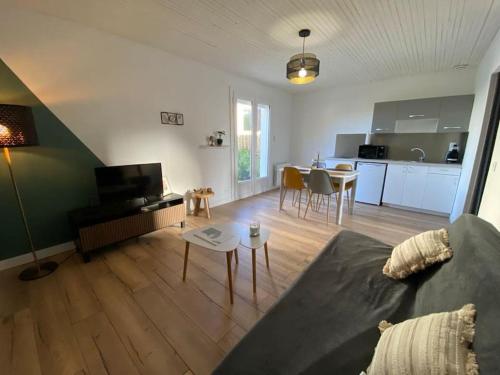 a living room with a couch and a table and a kitchen at Maisons Martigny B - Proche Futuroscope et Aquascope in Chasseneuil-du-Poitou