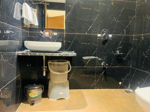 a black tiled bathroom with a sink and a toilet at Hotel Royal Empire in Gandhinagar