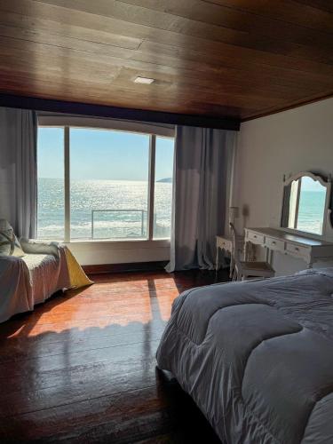 a bedroom with a bed and a view of the ocean at Casa pe na areia em Buzios in Búzios
