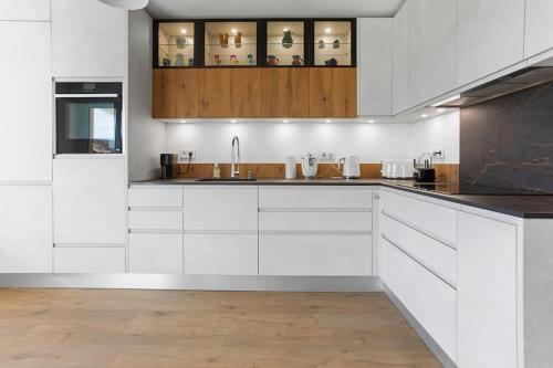 une cuisine avec des armoires blanches et un évier dans l'établissement Appt 120m2 Vue mer 2 min du centre, à Saint-Raphaël