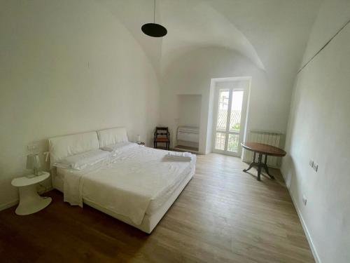 a white bedroom with a bed and a table at Le Volte di via Portica - Deluxe Apartments Italia in Assisi