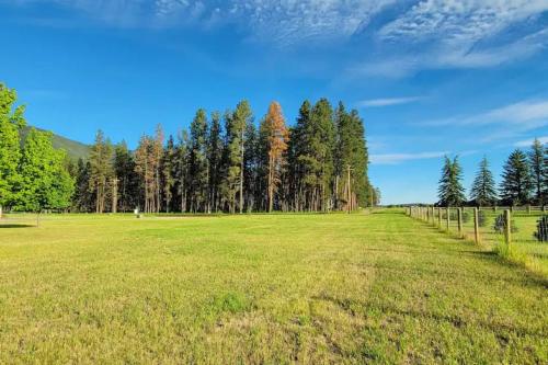 un gran campo de césped con árboles en el fondo en Charming Chalet Close to GNP, Downtown & Game Room!, en Columbia Falls