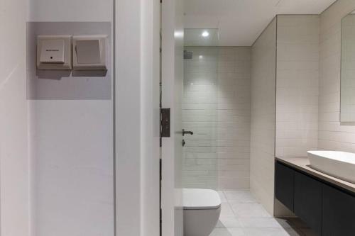 a white bathroom with a toilet and a sink at Sahab - Black Edition One BR Apartment in Sharjah