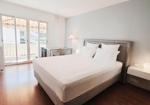 une chambre avec un grand lit avec des draps et des oreillers blancs dans l'établissement Brise marine Croisette, à Cannes