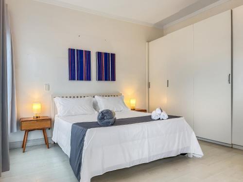 a bedroom with a large white bed with two lamps at 1 Suíte AC 50m da Praia Piscina Churasqueira in Guarujá