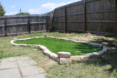 a backyard with a retaining wall and a yard with a grassy area at OceanView Oasis - Relax with Hot Tub, Breakfast, Fire Pit & Putting Green! in Panama City Beach
