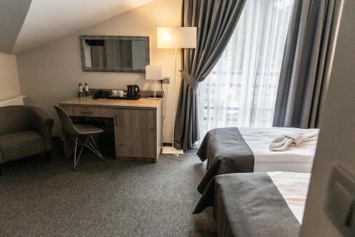a hotel room with two beds and a desk and a window at Jurajski Kryształ in Zaborze