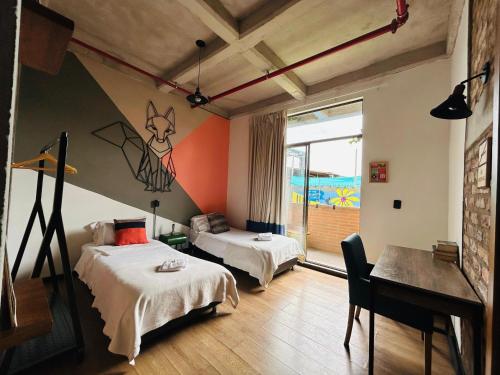 a bedroom with two beds and a desk and a window at Socialtel Candelaria Bogotá in Bogotá