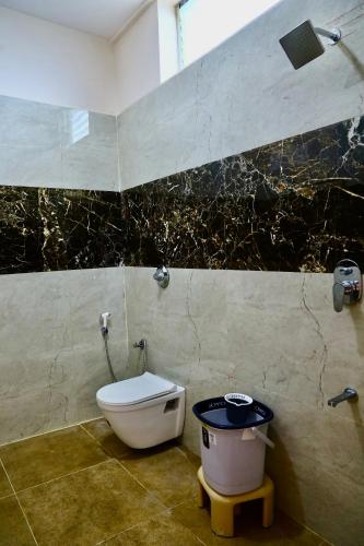 a bathroom with a toilet and a trash can at Gokulam Grand in Srikalahasti