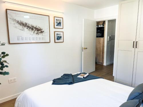 a white bedroom with a bed and a picture on the wall at IMROF - Mountain Lodge in Escarrilla