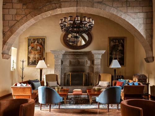 a living room with a fireplace and chairs and a chandelier at Monasterio, A Belmond Hotel, Cusco in Cusco