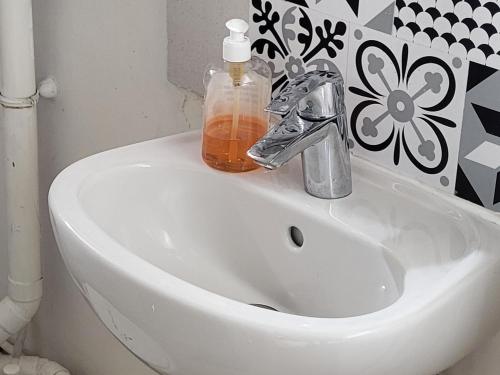 - un lavabo blanc avec une bouteille de savon dans l'établissement Cosy Appartement Paris Ouest, à Suresnes
