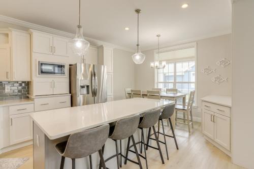 a kitchen with white cabinets and a large island with bar chairs at Lakeside Marblehead Home with Screened Patio! in Mineyahta-on-the Bay