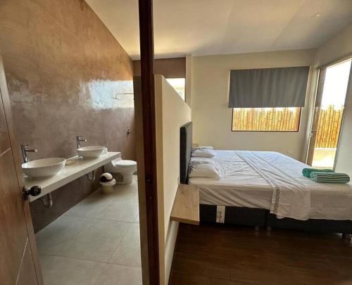 Un dormitorio con una cama y un baño con lavabo. en La casa de Diego, en Los Órganos
