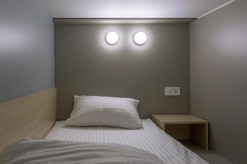 a bedroom with a bed with two lights on the wall at CAPSULE HOTEL & HOSTEL in Kharkiv