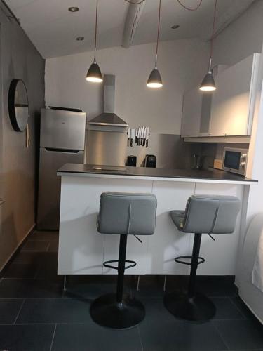 une cuisine avec deux tabourets de bar et un comptoir dans l'établissement Comme chez Soi, à Martigues