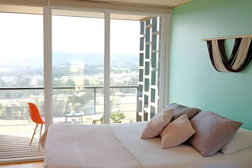 a bedroom with a white bed and a large window at Cabañas del cerro 2 in Pichilemu