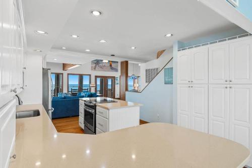 a kitchen with white cabinets and a living room at Sunrise to Sunset Oceanfront Home with Creek Dock in Pawleys Island