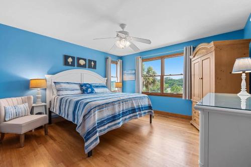 a blue bedroom with a bed and a window at Sunrise to Sunset Oceanfront Home with Creek Dock in Pawleys Island