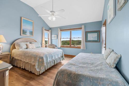 a blue bedroom with two beds and a window at Sunrise to Sunset Oceanfront Home with Creek Dock in Pawleys Island