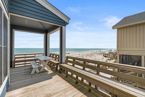 a porch with a bench and a view of the beach at Sunrise to Sunset Oceanfront Home with Creek Dock in Pawleys Island