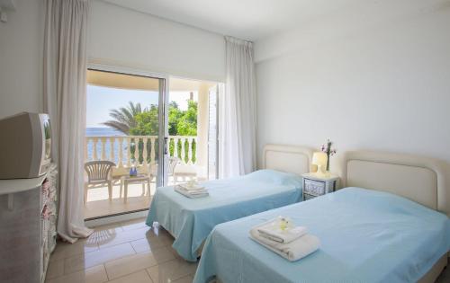 ein Hotelzimmer mit zwei Betten und Balkon in der Unterkunft Luxury Villa With Special Sea Views in Meneou