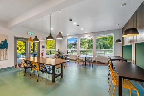 a dining room with tables and chairs and windows at Nowhere Special Hostel in Rossland