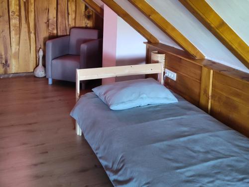 a bed in a attic room with a chair at Ruralna kuća za odmor Brezanka, Zagrebačka ulica 21 Gornja Stubica in Gornja Stubica
