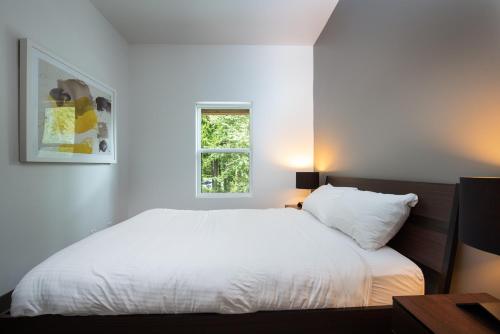 a bedroom with a white bed and a window at Nowhere Special Hostel in Rossland